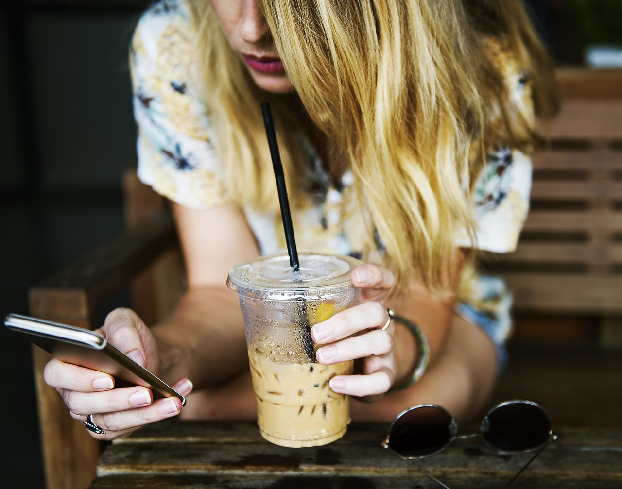 image: girl checking phone and drinking coffee