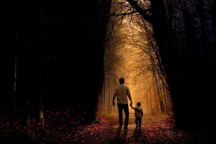 image: father and son holding hands walking through forest