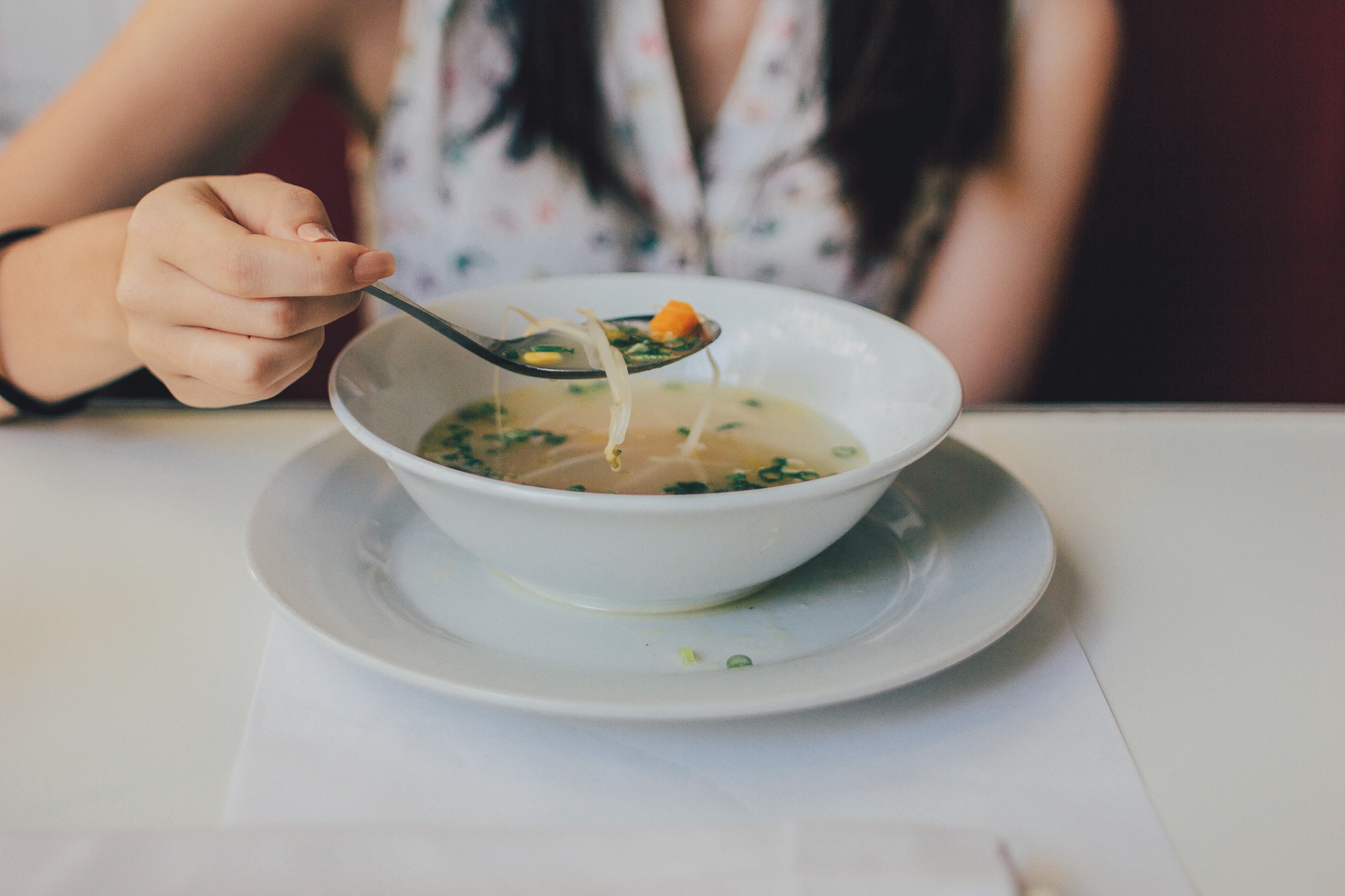 image: woman eating healthy soup at table