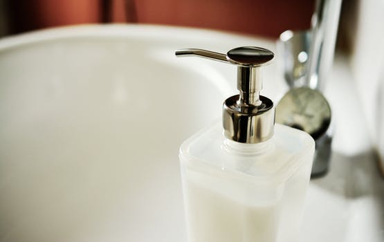 image: clean white bathroom sink and soap dispenser