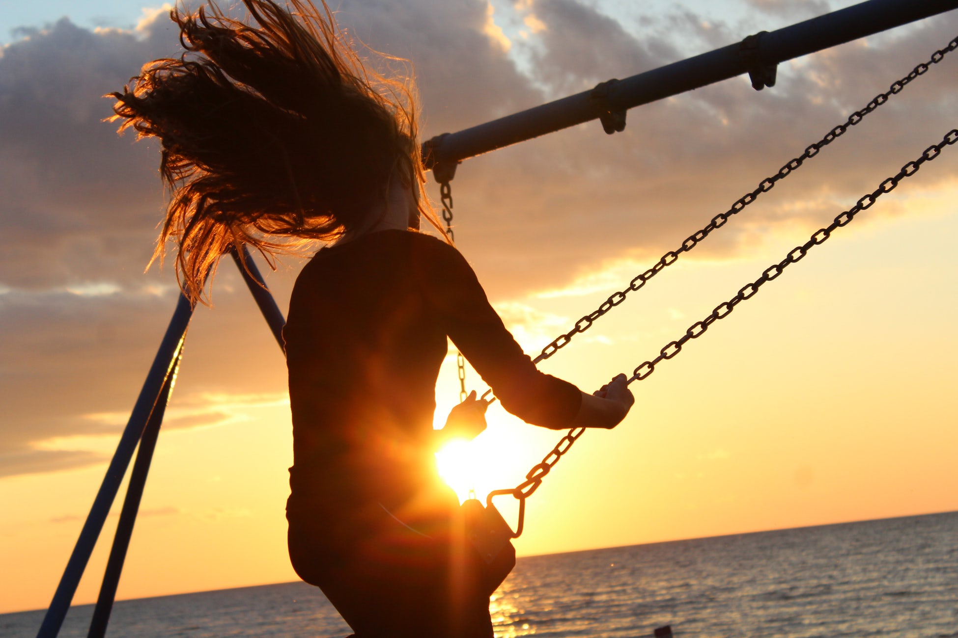 image: Woman swinging on a swing at sunset